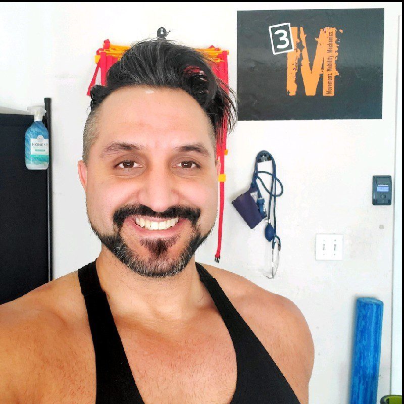 A man with a beard and mustache wearing a black tank top.