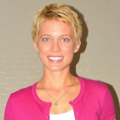 A woman with short blonde hair wearing pink.