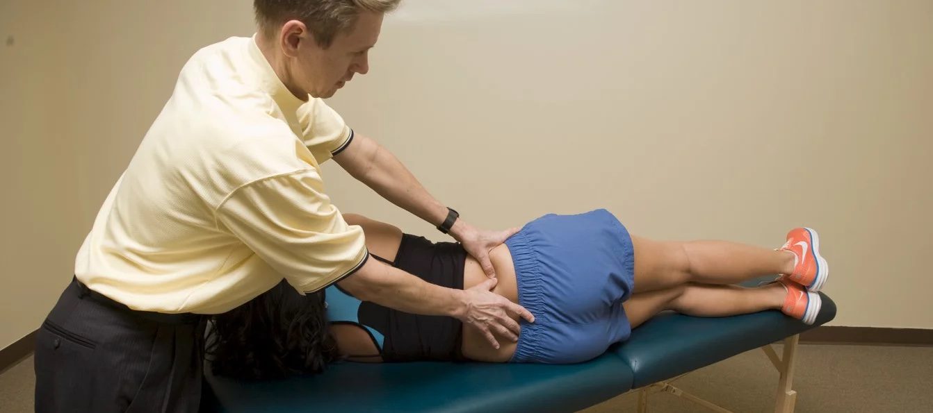 A person is getting their back examined by an osteopath.