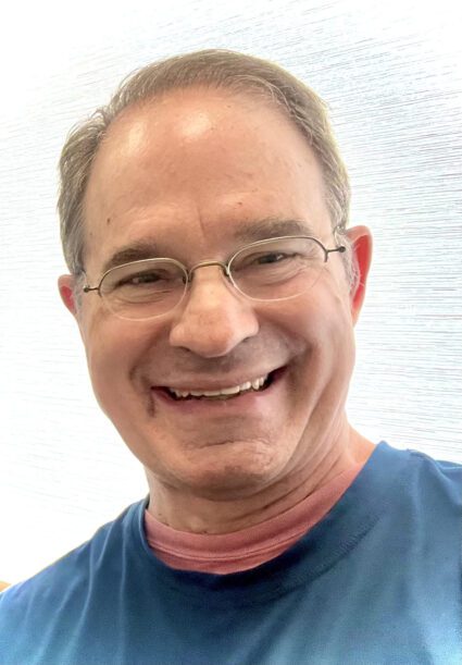 A man with glasses smiling for the camera.